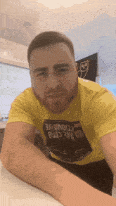a man with a beard wearing a yellow t-shirt that says ' da crab ' on it