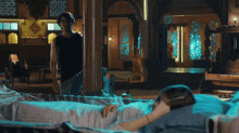 a man standing next to a woman laying on a bed in a room