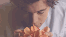 a close up of a man smelling a flower petal