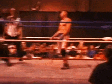 a man is standing in a boxing ring with a referee watching .