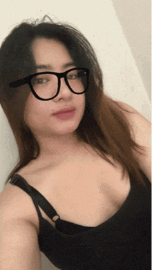 a woman wearing glasses and a black top takes a selfie