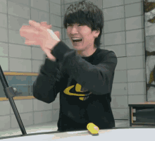 a man wearing a black shirt with the letter c on it is clapping his hands