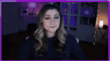 a woman is making a heart with her hands in front of a purple background .
