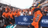 a race car driver is walking in front of a crowd of people with a sign that says crypto.co.