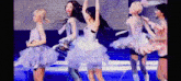a group of women in tutus are dancing on a stage in front of a microphone .