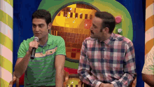 a man speaking into a microphone while another man looks on
