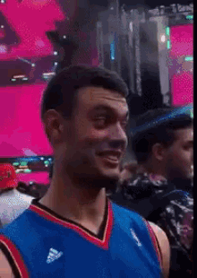 a man wearing a blue and red jersey is smiling in a crowd .
