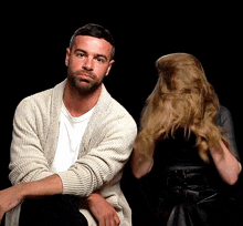 a man with a beard is sitting in front of a woman holding her hair