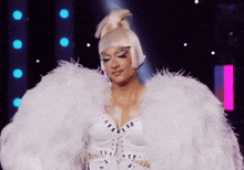 a woman is wearing a white feathered outfit and a wig