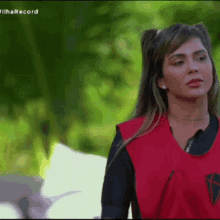 a woman in a red vest is standing in front of a green background