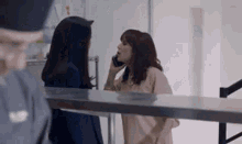 a woman is talking on a cell phone while another woman stands behind her .