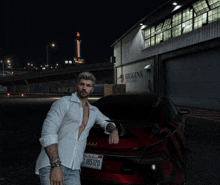 a man in a white shirt leans on a red car with a license plate that says b165120