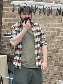 a man in a plaid shirt stands in front of a clothes line