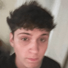 a close up of a young man 's face with a blurred background making a funny face .