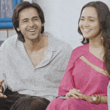 a man and a woman are sitting next to each other and laughing