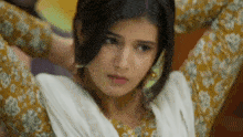 a close up of a woman wearing a yellow and white floral dress with her arms outstretched .