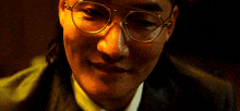 a close up of a man wearing glasses and a suit with a ponytail .