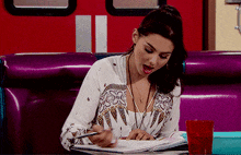 a woman sits at a table in a diner looking at a notebook