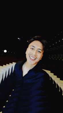 a man in a black shirt is smiling in front of a row of stairs