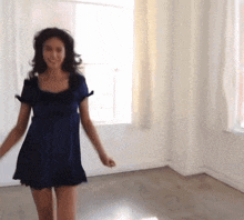 a woman in a blue dress is dancing in front of a window .
