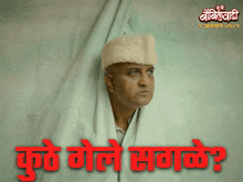 a man wearing a white fur hat is behind a white cloth with the words " kure gole sagake " in red