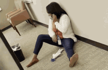 a woman sits on the floor talking on her phone
