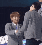 two men in suits are shaking hands and one has the number 11 on his jacket