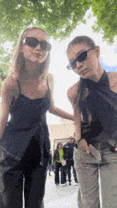 two women wearing sunglasses pose for a picture together
