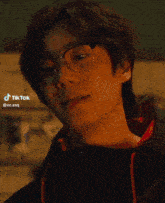 a close up of a man wearing glasses and a tik tok sticker