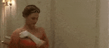 a woman in a pink dress is standing in a hallway with a man in a suit in the background .