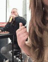 a man is drinking a beer in front of a coca cola fridge