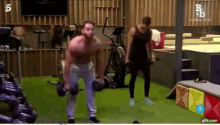 a man is lifting a dumbbell in a gym while another man watches .