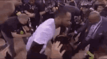 a man in a white shirt is kneeling down in front of a crowd .
