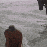 a shirtless man is kneeling on the beach near the ocean