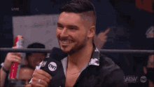 a man is holding a microphone in a wrestling ring and talking into it .