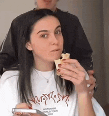 a woman is eating an ice cream cone while holding a cell phone in her hand .