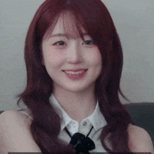 a woman with red hair and a white shirt smiles for the camera