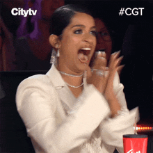 a woman applauds in front of a cup that says cgt