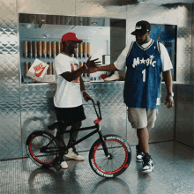 a man wearing a blue magic jersey talks to another man