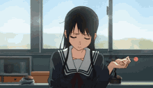 a girl in a school uniform is holding a red lollipop in her hand