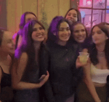 a group of women are posing for a picture and one of them is holding a cup