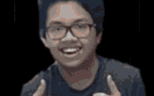 a young man wearing glasses is smiling and holding a cell phone in his hand .