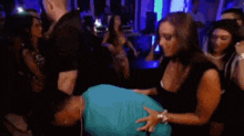a woman is holding a man 's butt in a crowded room at a party .