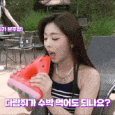 a woman is eating a slice of watermelon while sitting on a chair .