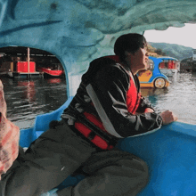 a man wearing a life vest is sitting in a boat on a lake