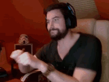 a man with a beard is wearing headphones and playing a video game while sitting in a chair .