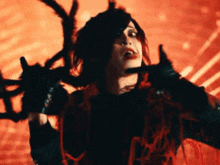 a woman in a black and red costume is holding a sword