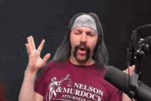 a man with long hair and a beard is talking into a microphone .