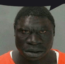 a man with a very serious look on his face is wearing an orange shirt