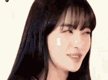 a close up of a woman 's face with long black hair and bangs making a funny face .
